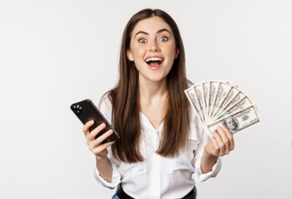 A woman holding up currency and a cell phone.
